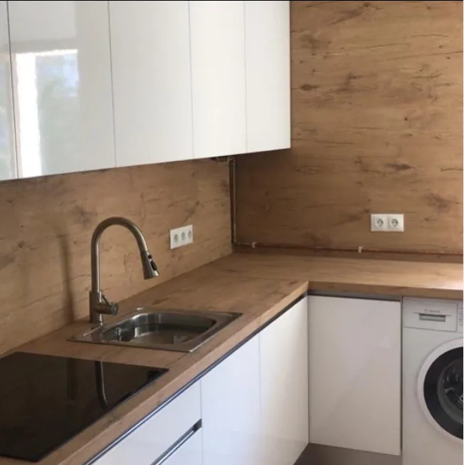 Cocina funcional con revestimiento de madera y muebles blancos